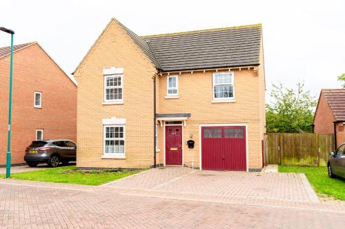 a brick house with a red door on a street at The Grace House Entire 4bed detached in Peterborough