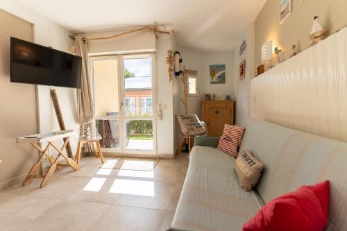 ein Wohnzimmer mit Sofa und Fernseher in der Unterkunft Appartement pour 4 pers avec piscine tennis et parking 56 in Le Touquet-Paris-Plage