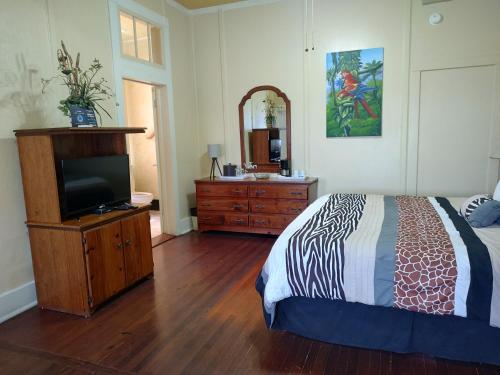 a bedroom with a bed and a dresser with a television at The Great House Inn in Belize City