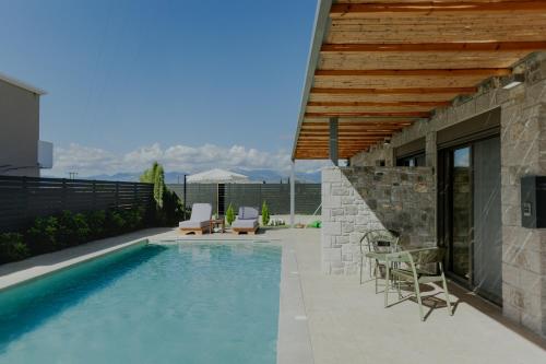 a swimming pool with chairs next to a house at NIAMA Luxury apartments Nafplio in Nafplio
