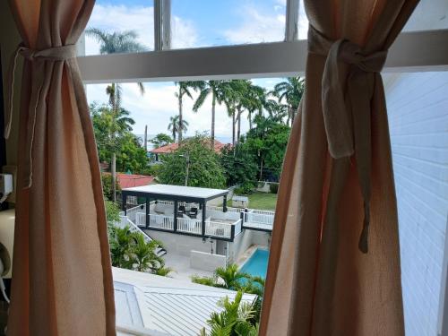 a window with a view of a pool and palm trees at The Great House Inn in Belize City