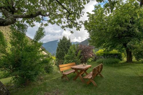 une table et un banc en bois dans un champ arboré dans l'établissement Gîte Le Robinson, à Saint-Martin-Vésubie