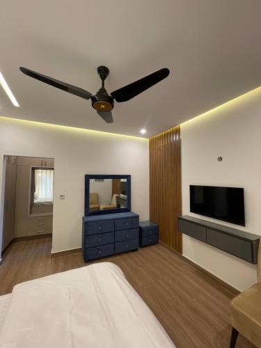 a bedroom with a ceiling fan and a television at Fellows BnB in Dhok Sandemār