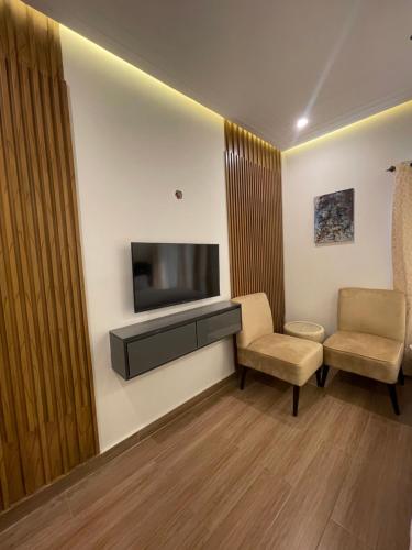 a room with two chairs and a flat screen tv at Fellows BnB in Dhok Sandemār