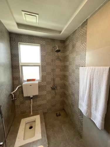 a bathroom with a toilet and a window at Fellows BnB in Dhok Sandemār