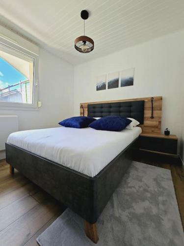 une chambre avec un lit avec des oreillers bleus dessus dans l'établissement Splendide appartement Standing Piscine, à Gérardmer