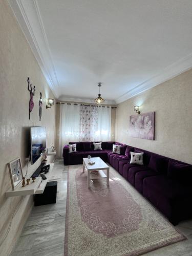 a living room with a purple couch and a tv at Charmant appartement á Tanger in Tangier