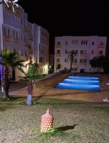 a swimming pool in front of a building at night at Charmant appartement á Tanger in Tangier