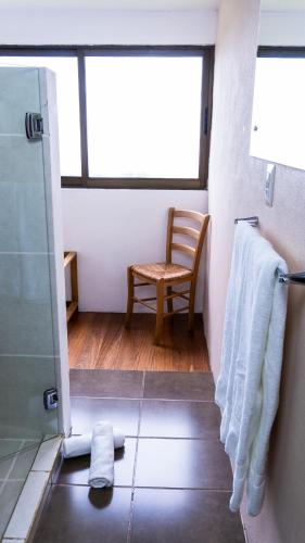 a bathroom with a shower and a chair and a window at Poas Volcano Lodge in Vara Blanca