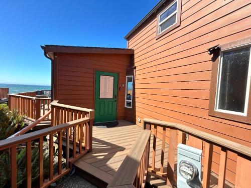 a house with a wooden deck with a green door at Ocean Front Cabin 15, Jacuzzi & Sensational Views in Smith River