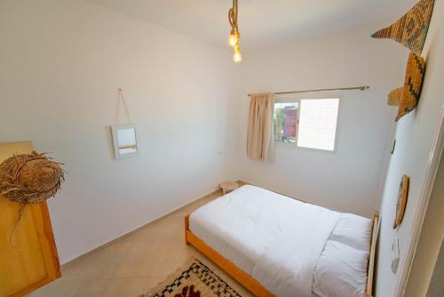 a small bedroom with a bed and a window at Surf Break Morocco in Imsouane
