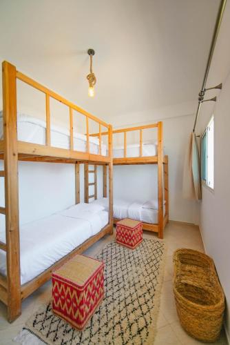 a room with two bunk beds and a rug at Surf Break Morocco in Imsouane
