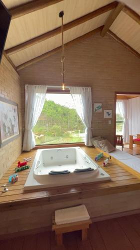 a large bath tub in a room with a large window at Chalés Villa Caravaggio in Santa Teresa