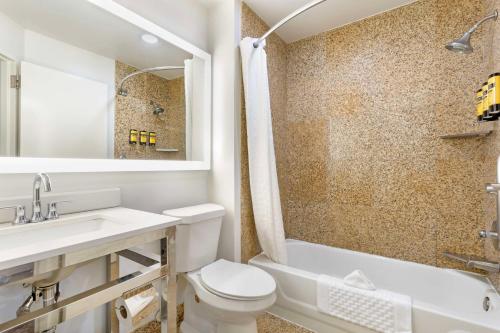 a bathroom with a toilet and a sink and a tub at Best Western Plus Sugar Land-Stafford in Sugar Land
