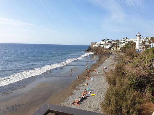 a group of people on a beach near the ocean at Apartamento Playa Cañon del águila in Playa del Aguila