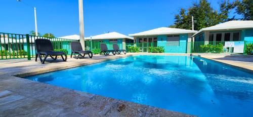 a swimming pool with chairs next to a house at Villas at Chalet De Buye in Cabo Rojo