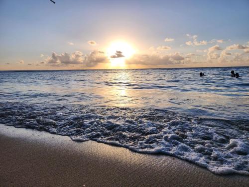 a sunset over the ocean with people in the water at Villas at Chalet De Buye in Cabo Rojo