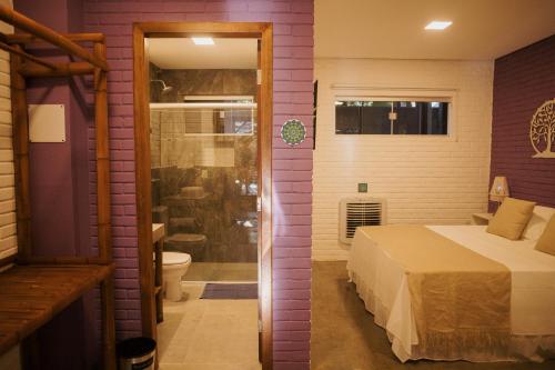 a bedroom with a bed and a bathroom with a shower at Pousada Egrégora in Sao Jorge