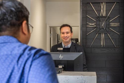 a man standing at a desk in front of a mirror at Crowne Plaza Fredericton Lord Beaverbrook by IHG in Fredericton
