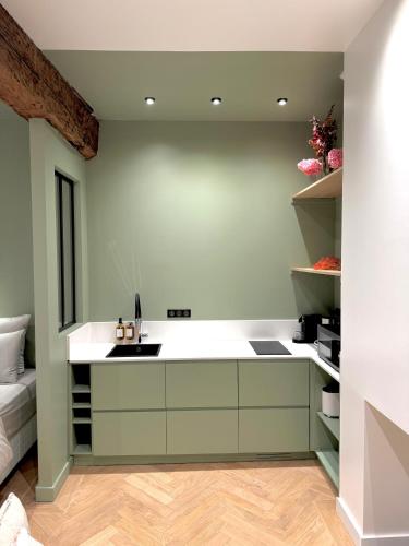 une cuisine avec des armoires vertes et des comptoirs blancs dans l'établissement Sur les traces de Cyrano, à Bergerac