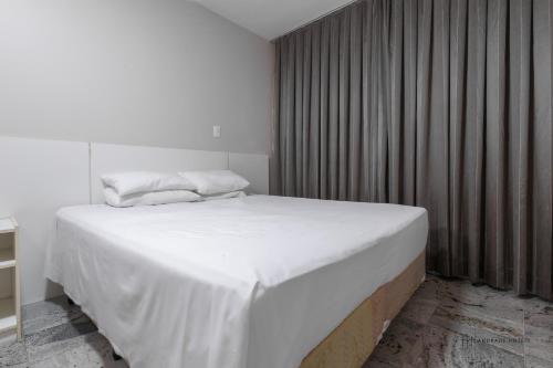 a bedroom with a large white bed and a window at Rede Andrade Pampulha in Belo Horizonte