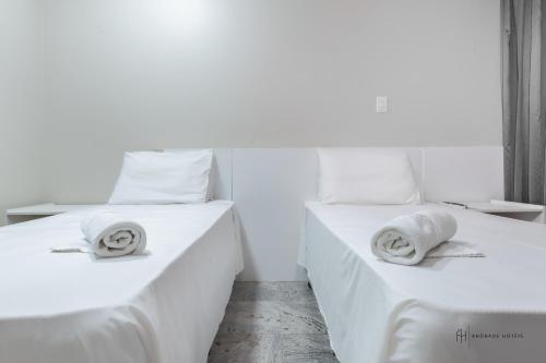 two beds in a room with white sheets and pillows at Rede Andrade Pampulha in Belo Horizonte