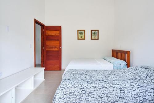 a bedroom with two beds and a door at Casa Caiçarinha perto do centro com ar e piscina in Paraty