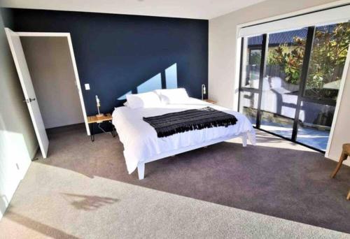 a bedroom with a white bed with a blue wall at Miss Eastons Whare in Westport