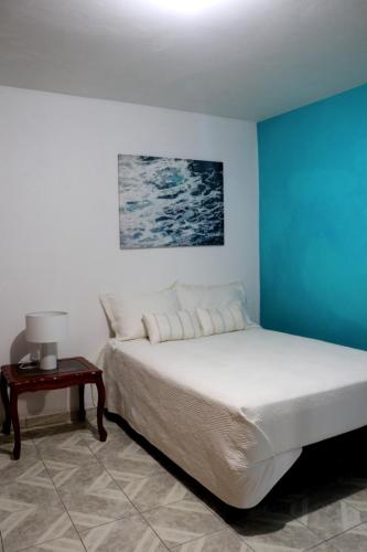 a bedroom with a bed with a blue wall at Departamento Bugambilias in Oaxaca City