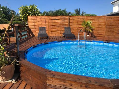 a large swimming pool on a wooden deck with two chairs at Lodge Moorea Vaikea in Papetoai