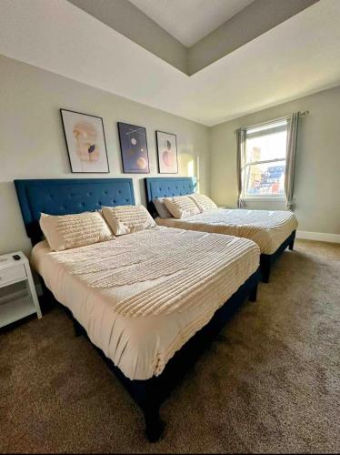 two beds in a bedroom with a blue headboard at Family-Friendly 4BR Retreat Sleeps 12, Private Yard, Garage, Close to Stadiums, Casino & Downtown in Pittsburgh