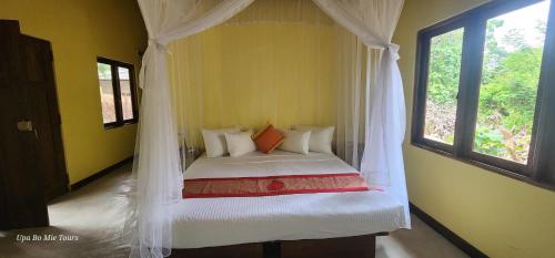 a bedroom with a canopy bed with a window at Undiya The Neighborhood Sigiriya in Sigiriya