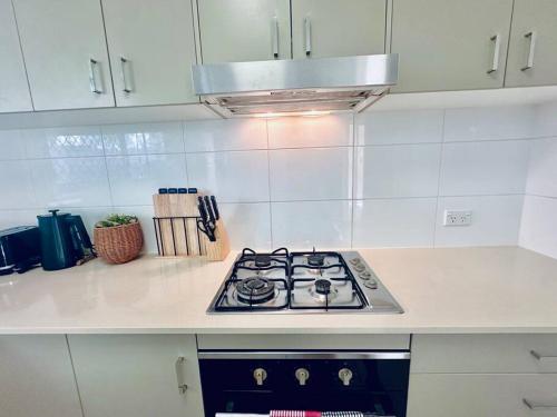 a stove top oven in a white kitchen at Calm Hideaway - Townhouse with Pool Access & Garage in North Lakes