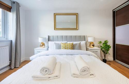 a bedroom with a large white bed with two white towels at Classic 2bedroom Apartment in Mill Hill