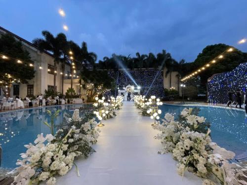a wedding aisle with white flowers and lights at Dakruco Hotel in Buon Ma Thuot