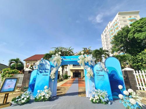 a blue arch with white flowers in front of a building at Dakruco Hotel in Buon Ma Thuot