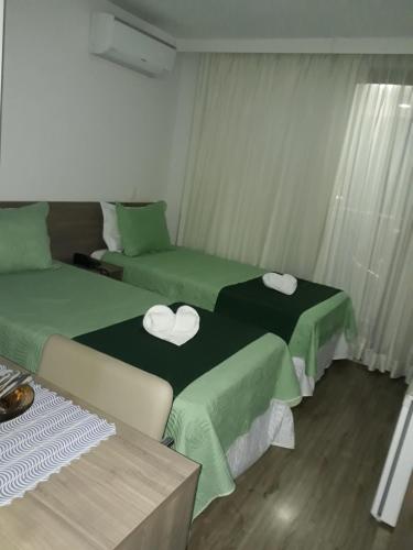 two beds in a room with green sheets at Via Première - Suíte - Riocentro - Barra Olímpica - Vista Panorâmica in Rio de Janeiro