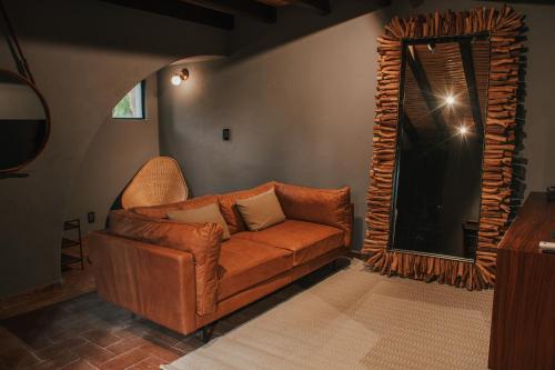 a brown leather couch in a living room with a mirror at Hotel Piedras Neg in San Miguel de Allende
