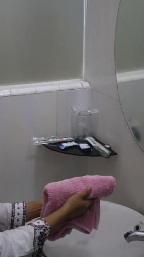 a woman laying on a bathroom sink with a pink towel at Nikita Hotel in Bukittinggi