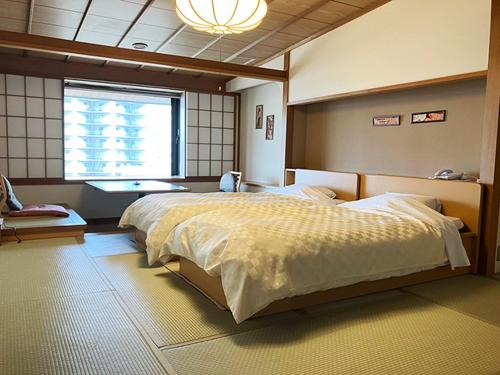 a bedroom with a large bed and a window at Yunokawa Kanko Hotel Shoen in Hakodate
