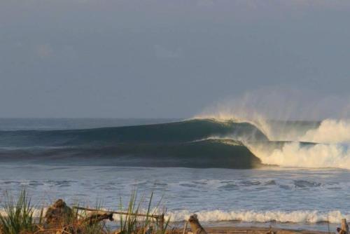 a large wave in the ocean on a beach at Hotel Beachfront Vista Hermosa in Jacó