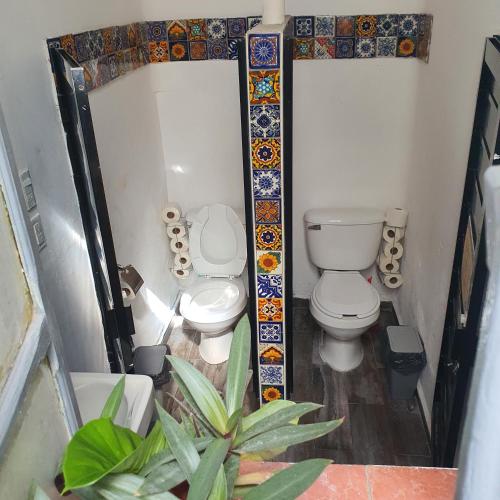 a bathroom with two toilets and tiles on the wall at Sukha Hostel San Luis in San Luis Potosí