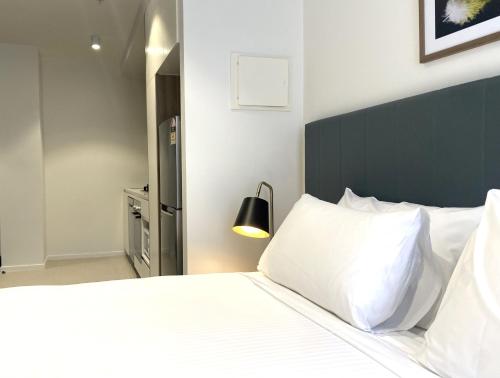 a bedroom with a white bed with a black headboard at Brady Apartment Hotel Hardware Lane in Melbourne
