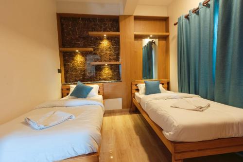 two beds in a room with blue curtains at A Square Residency Inn in Pokhara