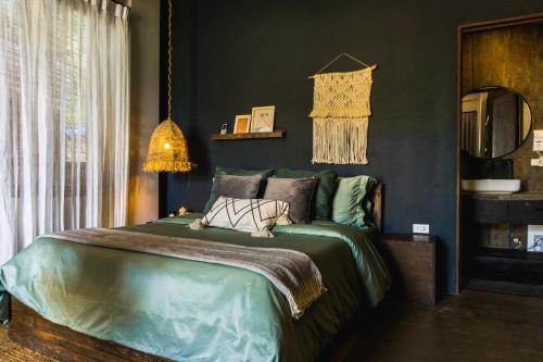 a bedroom with a large bed with green sheets at Happiness Villas in El Nido