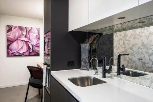 a kitchen with a sink and a painting on the wall at Balinese Charm meets Resort Living in Inner Sydney in Sydney