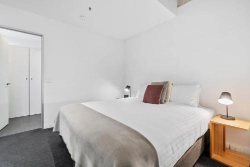 a white bedroom with a large bed and a table at Gibson Mill waterfront warehouse apartment - 104 in Hobart