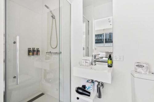 a white bathroom with a shower and a sink at Gibson Mill waterfront warehouse apartment - 104 in Hobart