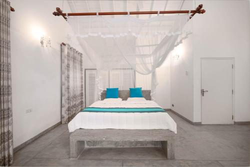 a white bedroom with a large bed with blue pillows at Tara Garden Sri Lanka - luxury colonial villa in Danwattegoda