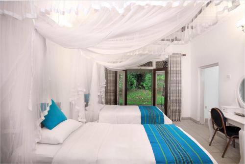 a white bedroom with two beds and a desk at Tara Garden Sri Lanka - luxury colonial villa in Danwattegoda